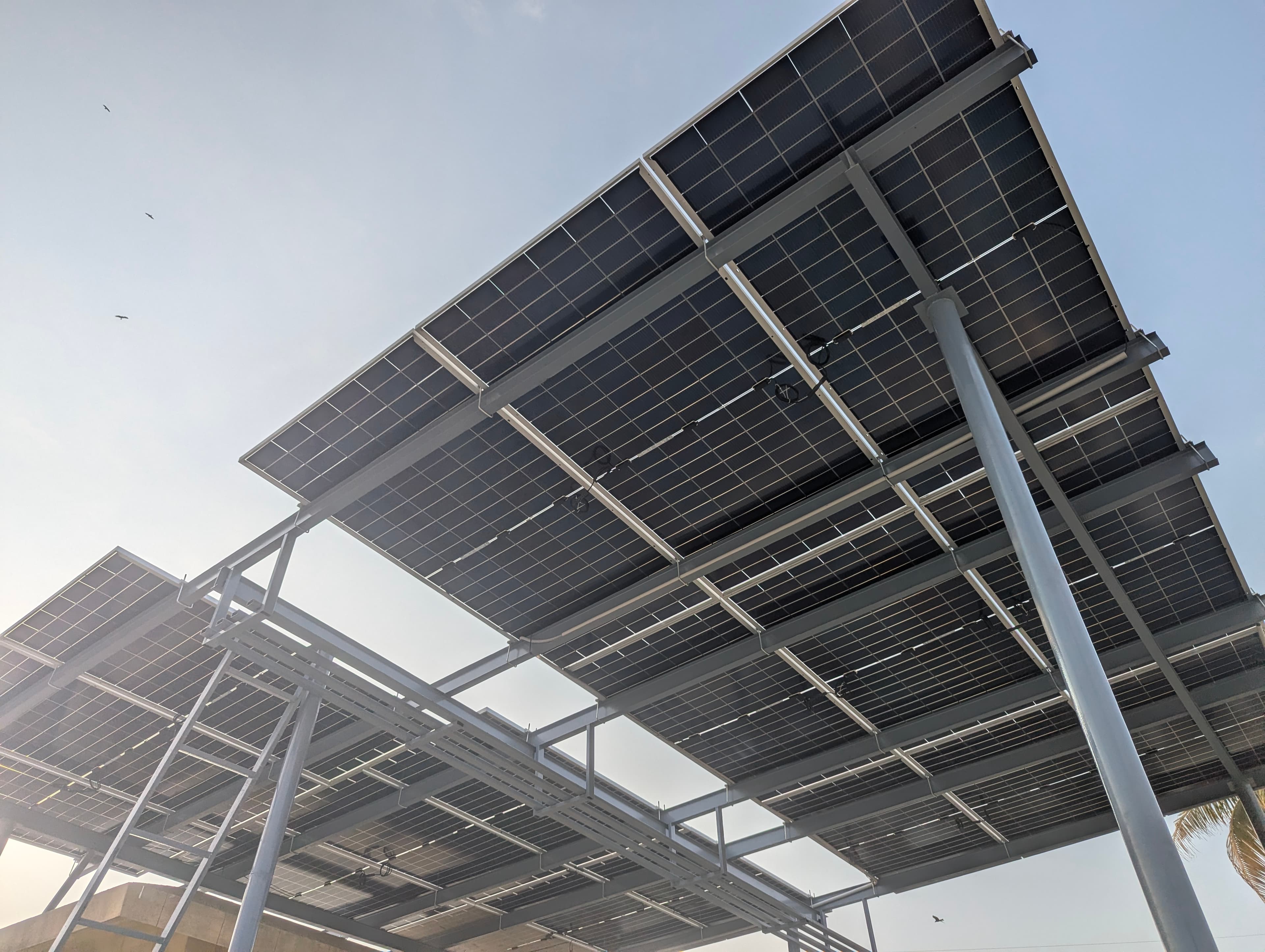 Tidy cable management and steel racking beneath an APC Solar carport installation in Karachi