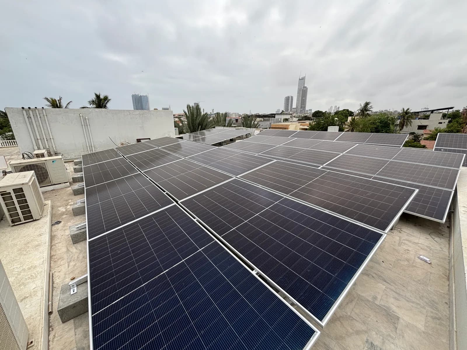 Flush-mounted rooftop solar array by APC Solar overlooking the Karachi skyline