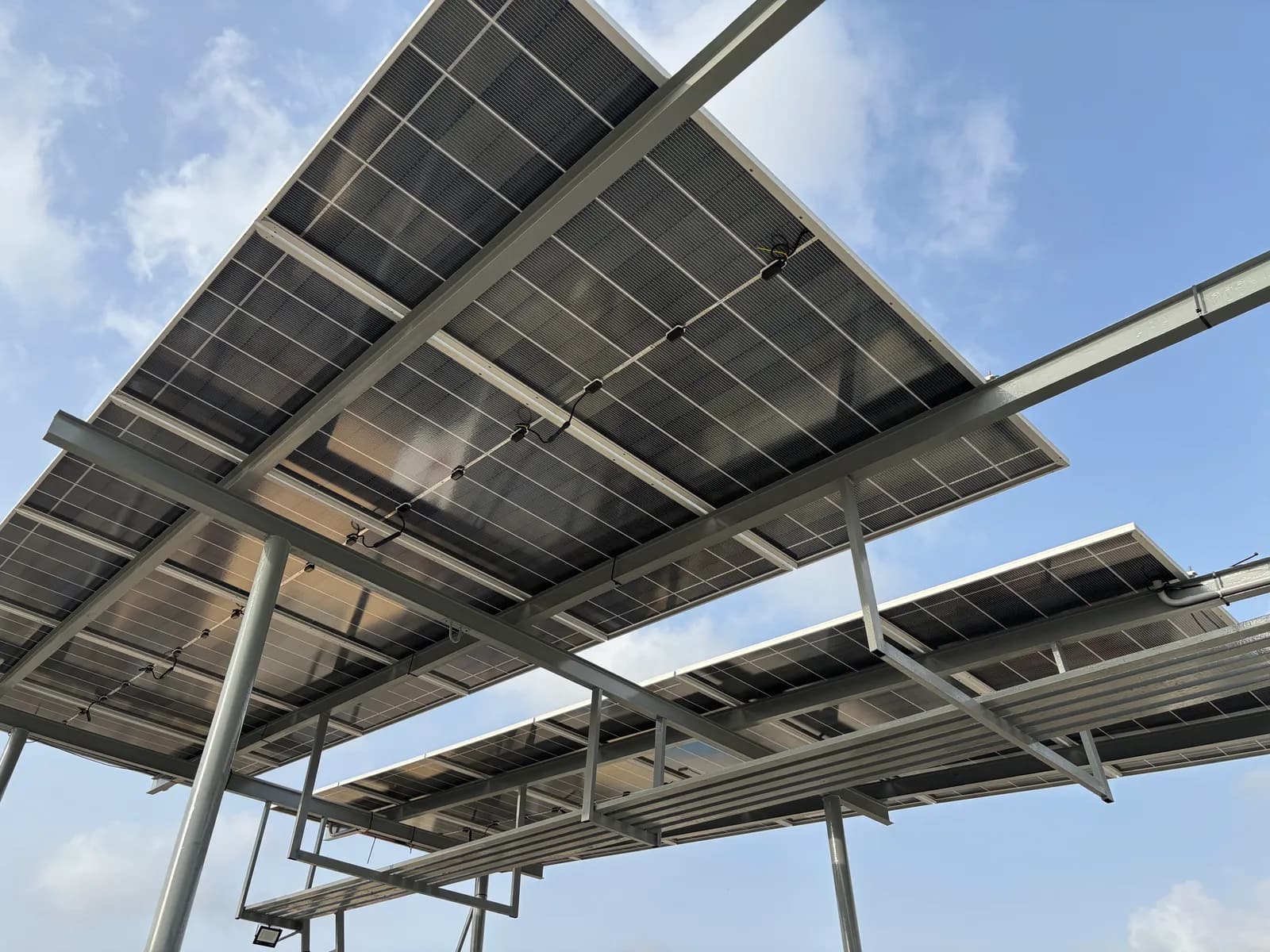 Elevated solar array raised high on tall steel columns by APC Solar in Karachi, seen against the sky