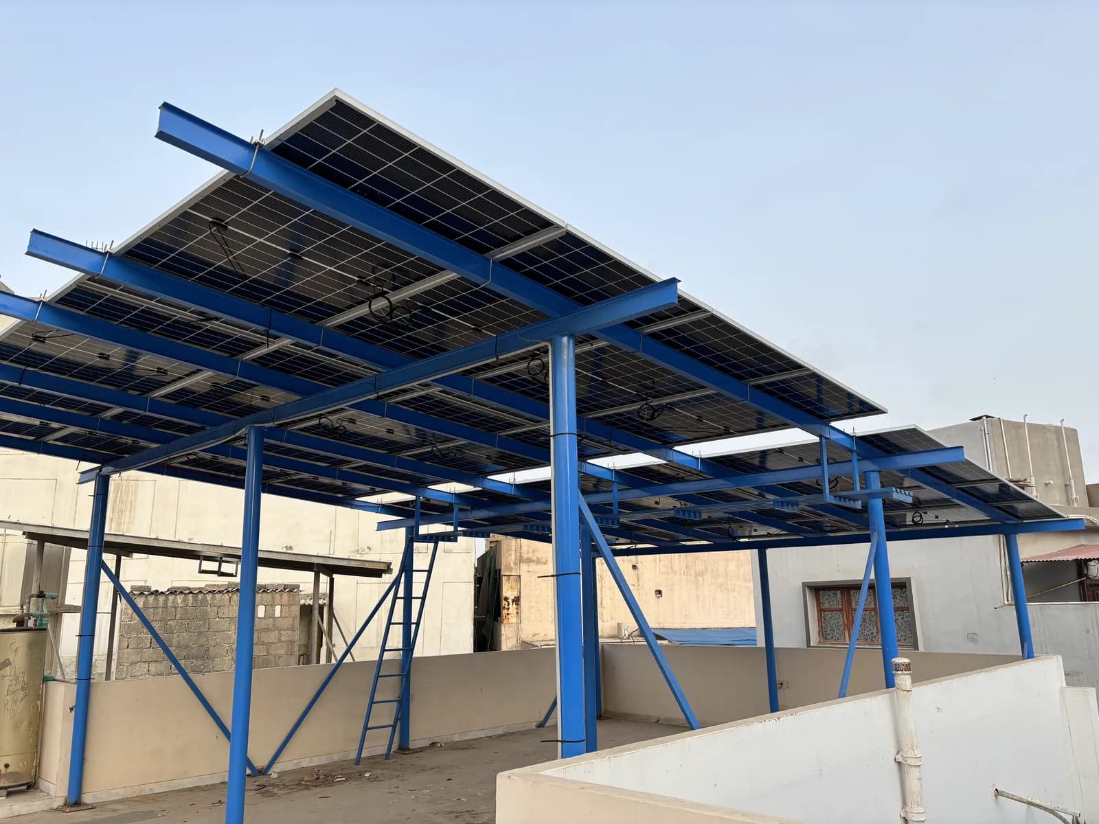 Elevated solar array on a powder-coated blue steel structure by APC Solar in Karachi